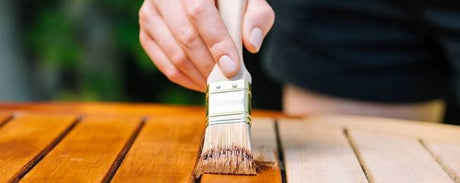 Applicazione di vernice protettiva su tavole di legno con pennello